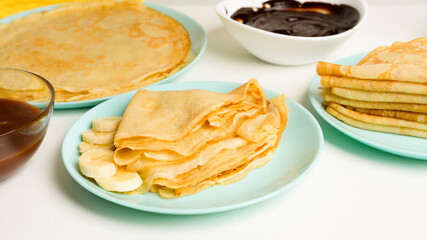 blini pancakes with banana and caramel, close-up on a blue plate on a light background . traditional Russian holiday is a symbol of spring and sweet dessert