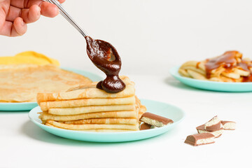blini pancakes with chocolate, close-up on a blue plate on a light background . traditional Russian...