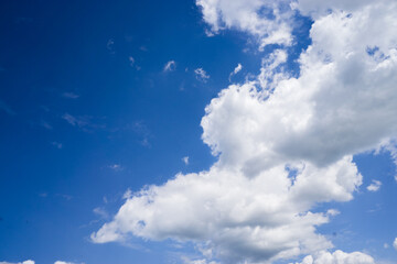 Naklejka na ściany i meble Bright cumulus clouds against a blue sky.