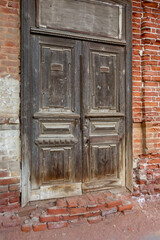 Old brown wooden double-wing door in an old brick building. Close-up.