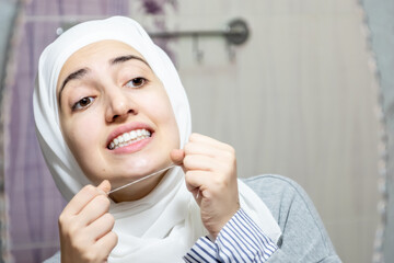 Arabic muslim woman cleaning her teeth with dental floss