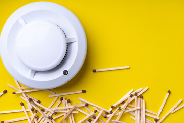 Fire detector and a bunch of matches on a yellow background
