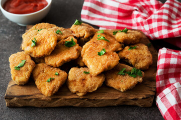 Homemade chicken nuggets with herbs and ketchup on a wooden board