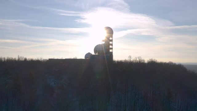 panning silhouette shot of abandoned observatory station on a hill in winter during sunset