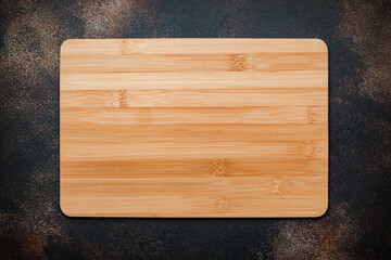 New rectangular bamboo wooden cutting board on stone background. Top view. Mock up for food project.