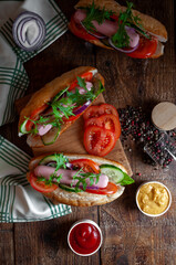 Hot dogs with herbs and vegetables on a wooden board