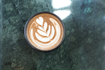 Top view of hot coffee latte foam design art isolated on green marble background. Barista crafts.