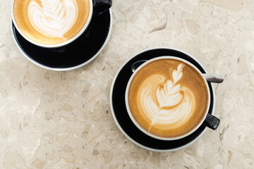 Top view of hot coffee latte foam of flower design art on beige marble table in cafe. Drink and beverage.