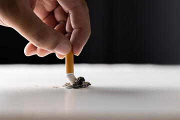 Close up hand putting out a cigarette. man extinguished his cigarette by crushing the floor. He...