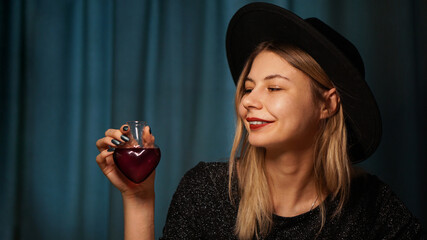 Cropped image of woman holding heart shaped glass jar of love potion. Beautiful young woman in a...