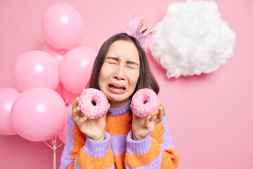 Photo of sad crying girl holds two doughnuts upest as none came to congratulate her with birthday...