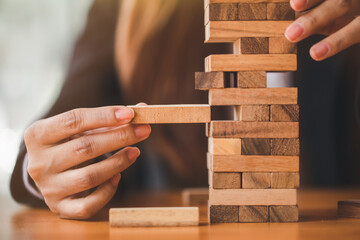 Woman's hand stacking wooden blocks  on a tower,. Business Planning,risk, strategy,development and...