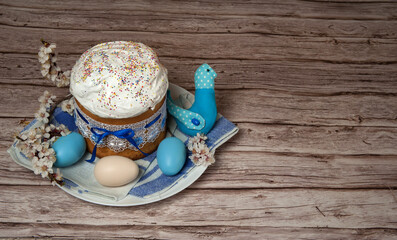 Easter composition. Eggs, apricot flowers, a cute handmade bird and a glazed Easter cake decorated with sugar sprinkles on a wooden background. Happy Easter Holidays. Free space.
