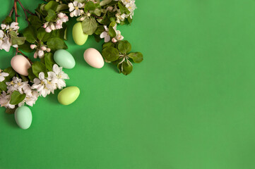 Easter composition. Blooming apple branches and colorful eggs on a green background. Happy Easter Holidays. Top view. Free space.