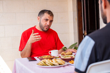 Muslim man and his friend are eating together and talking about many things