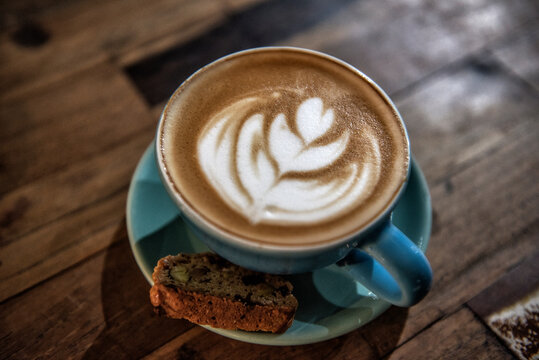 Cup of Piccolo latte with a Biscotti biscuit