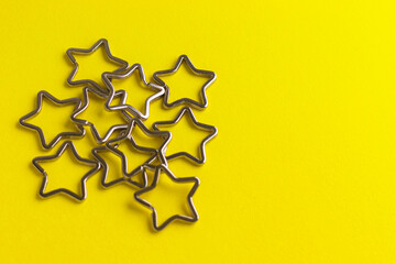 Heap of shiny metal split key rings for keychains. Chromium plated keychain clasp on yellow background. Flat lay, top view with copy space.