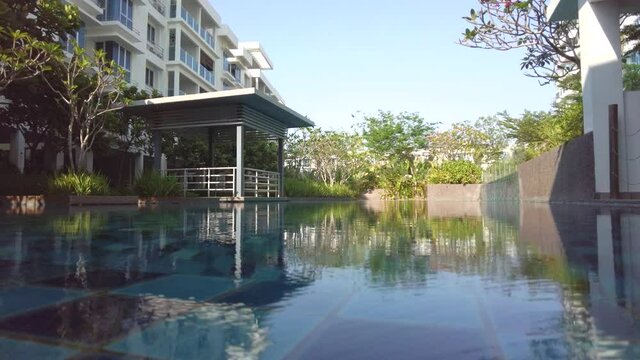 View of a modern apartment building with a swimming pool in the morning. Luxury resort concept. The footage contains noise due to low light.