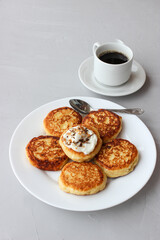 Breakfast of cheesecakes on a plate with sour cream.