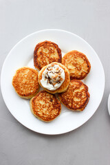 Breakfast of cheesecakes on a plate with sour cream.