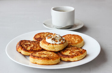 Breakfast of cheesecakes on a plate with sour cream.