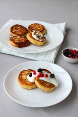 Breakfast of cheesecakes on a plate with sour cream.