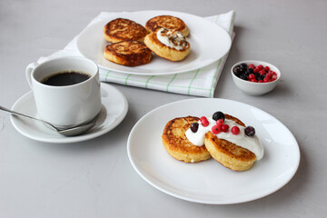 Breakfast of cheesecakes on a plate with sour cream.