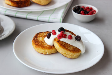 Breakfast of cheesecakes on a plate with sour cream.
