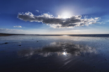 Fototapeta na wymiar Clouds reflection in Hauteville-sur-Mer beach