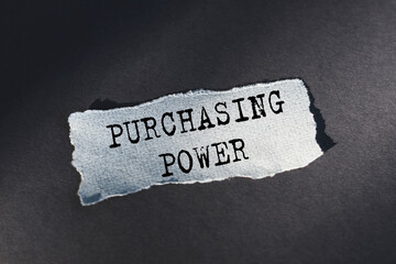 PURCHASING POWER. Text on torn paper on dark desk in sunlight.