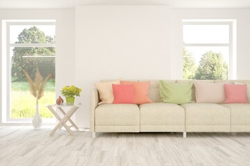 Minimalist living room in white color with sofa and summer landscape in window. Scandinavian interior design. 3D illustration