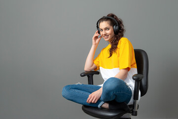 Fototapeta na wymiar teenager with long wavy hair dressed in a yellow t-shirt sitting on an office chair and listening music