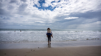 Asian girl riding piggyback on a asian guy at Malibu Beach, California, USA