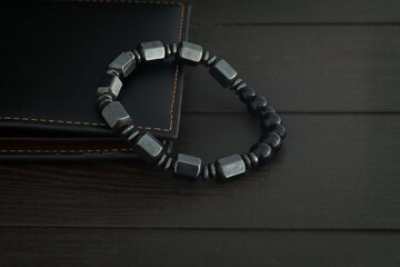 Round natural black stone bracelet on black wood table background, healthy stone bracelet