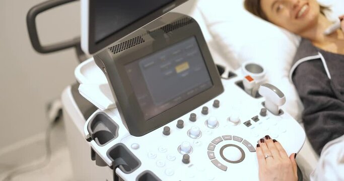 Doctor examining thyroid of female patient with ultrasound scan in medical spa. Concept of ultrasound examination and health checkup