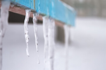 icicles hang on an iron painted surface. winter time . the cold came.