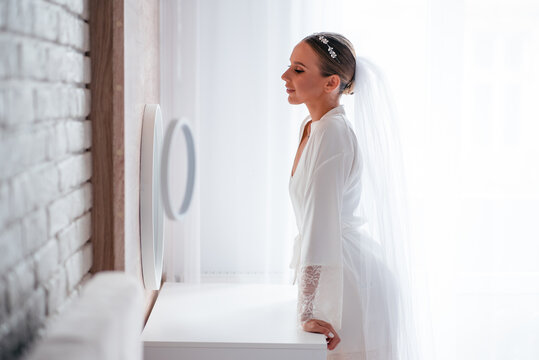 Happy bride in lingeria looking at mirror