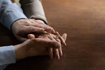 Senior mature man holding hand of beloved middle aged wife. Old family couple enjoys time together, expressing love, affection and support. Close up of arms with wedding ring. OAP Relationship concept