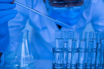 Biochemists are conducting experiments to discover new drugs. Work in science labs. A male scientist wearing protective goggles and garden gloves is dripping chemicals to test vaccine monkeypox virus