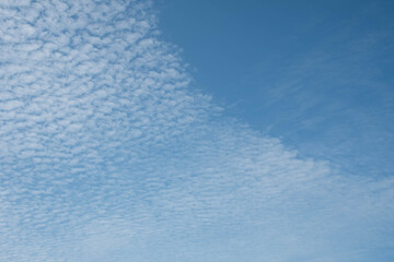 Fresh blue sky and soft white clouds, clean on a hot summer day. There is a copy space to put the design or text in the right of the image. The concept for the feeling of fresh weather.