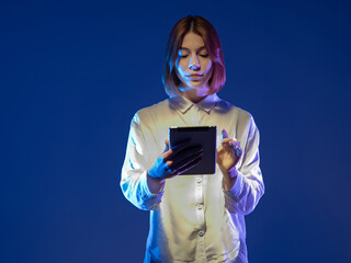 Young woman in trendy blouse holding tablet. Serious girl with tablet computer. Electronic tablet...