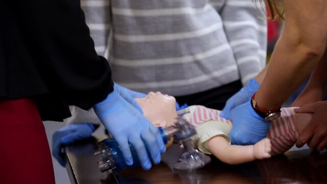 Practical medical course on a mannequin. Practitioners doing cardiopulmonary resuscitation on a baby doll. Chest compression and breathing. CPR medical training. - Powered by Adobe