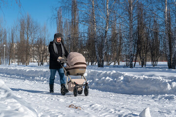 A bearded dad walks with a stroller in a city park.