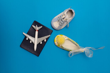 on the blue background airplane, american passport, baby girl shoe and baby boy shoe