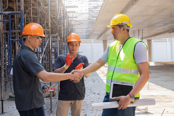 Teamwork, partnership, gesture concept. Builders greeting each other with handshake on construction site. construction workers in protective helmets and vests are shaking hands.