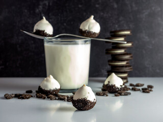 Cookies & Cream Cake Balls, truffle like dessert with a fresh glass of cold milk, a silver spoon, chocolate sandwich cookies and cookie crumbs.