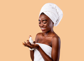 Smiling Black Woman In Towel Pouring Body Lotion On Palm
