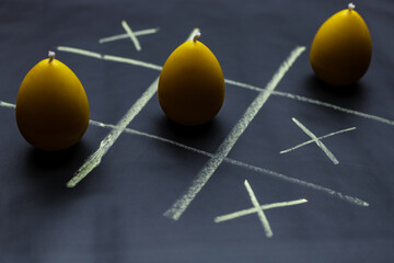 Playing tic tac toe or noughts and crosses with candles in the form of eggs.