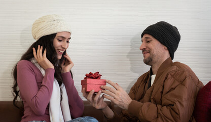 caucasian man giving gift to young girlfriend in anniversary day. They stay togerther at home.