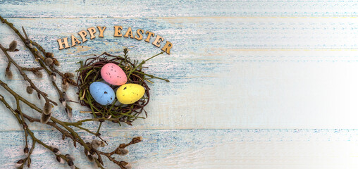 Happy Easter. Willow twigs. Holy Easter. Blue turquoise background. Easter eggs in the nest.